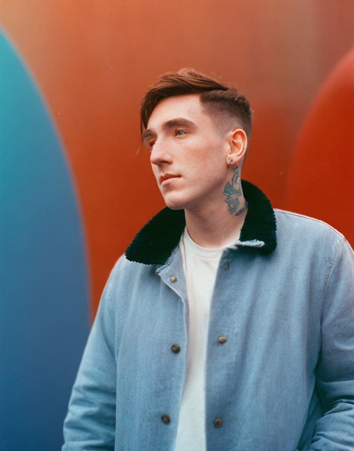 Tattooed young man gazes against colorful background