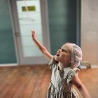 Child in Blue Dress Holding Red Balloon by Window with Light