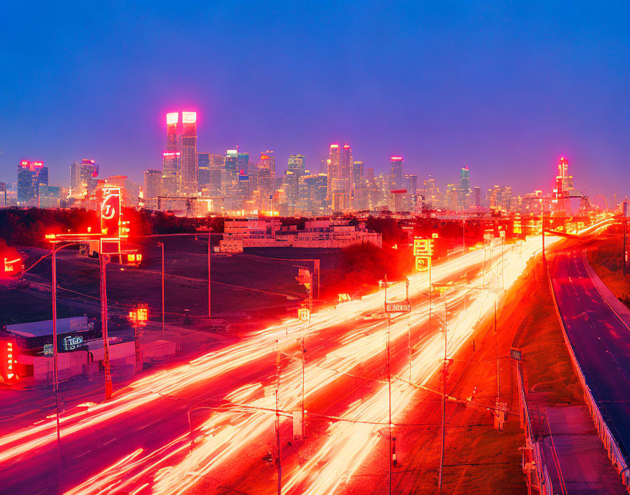 Urban skyline at dusk with illuminated skyscrapers and vehicle light streaks.