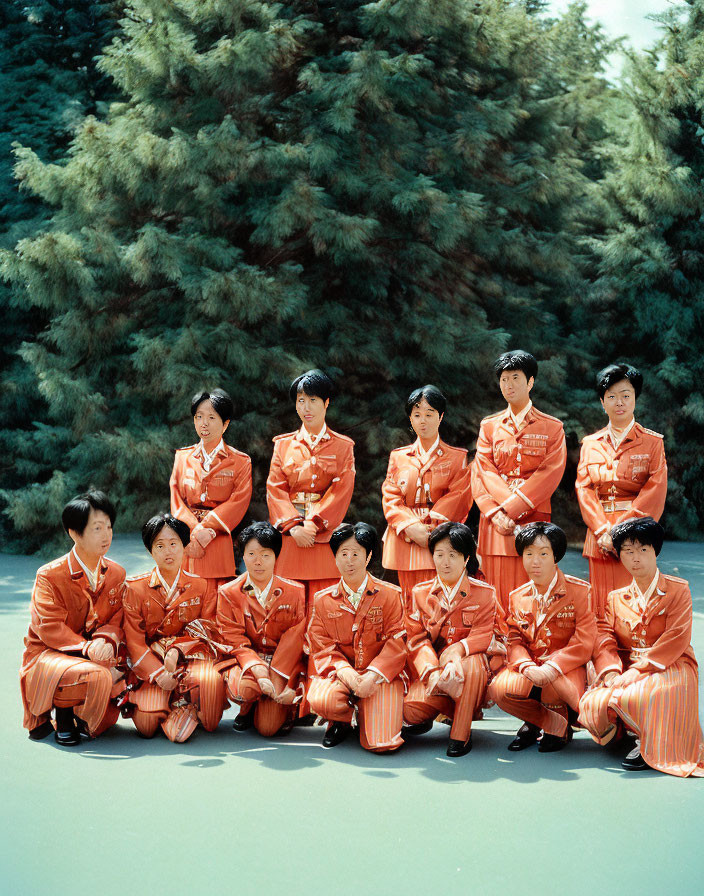 Group in Terracotta Uniforms Poses by Green Trees