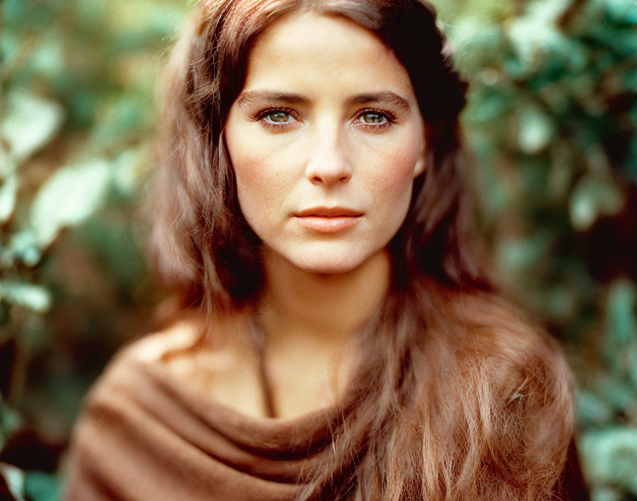 Brown-haired woman in shawl with blue eyes against green backdrop