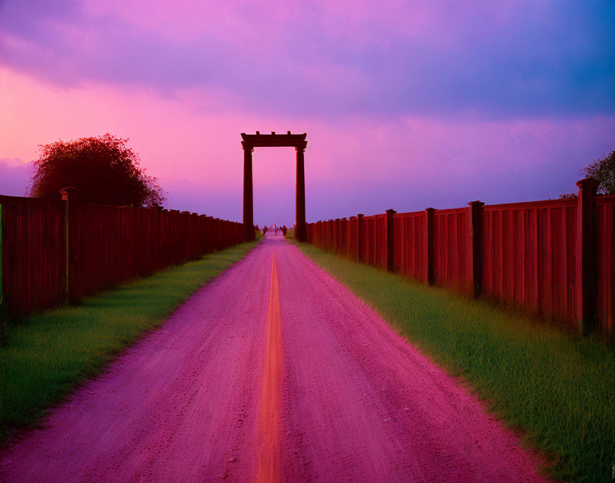 Twilight sky with purple and blue hues over dirt road and wooden gate