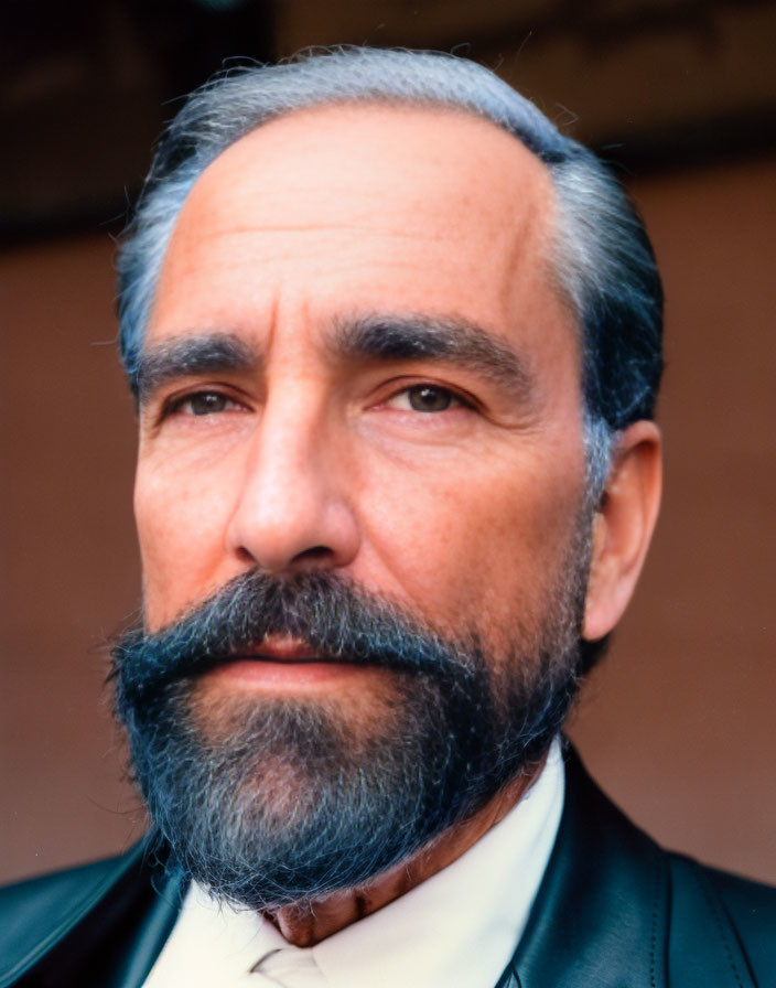 Serious man with graying beard in black suit & tie