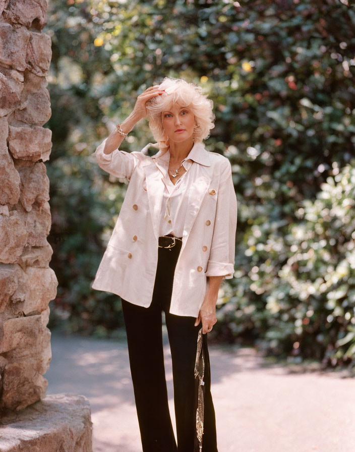 Blond woman in white blouse and black pants shading eyes outdoors