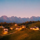 Mountain village at dusk with glowing lights nestled in hills under snow-capped peaks and twin moons.