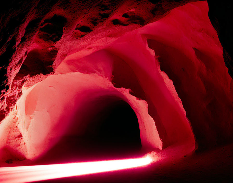 Vibrant red illuminated cave with textured walls and arched opening