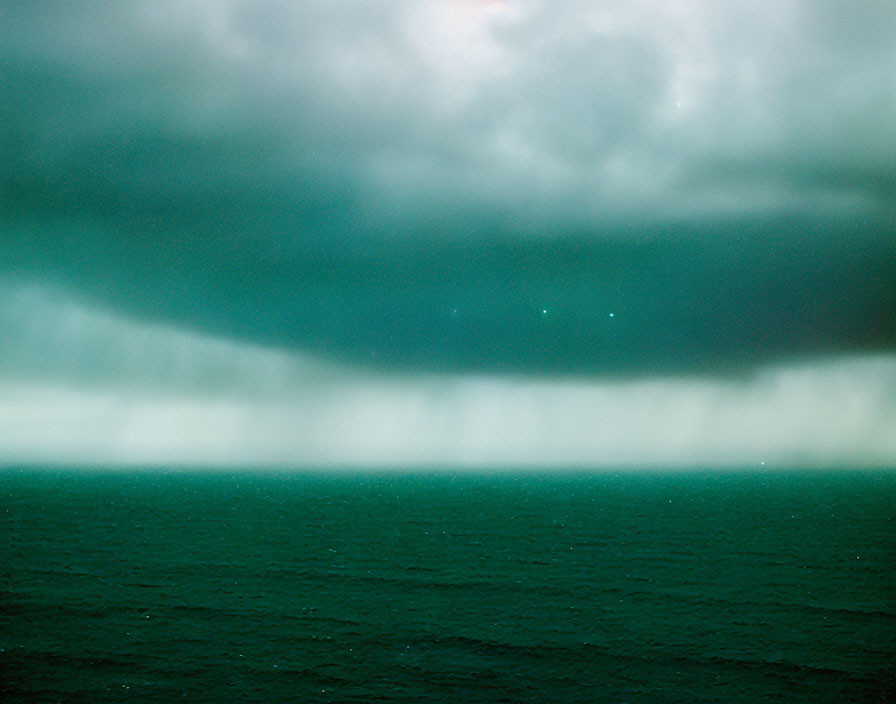 Tumultuous sea under green sky with looming storm cloud