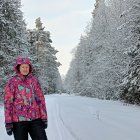 Person in Warm Attire with Backpack in Snowy Forest Sunset