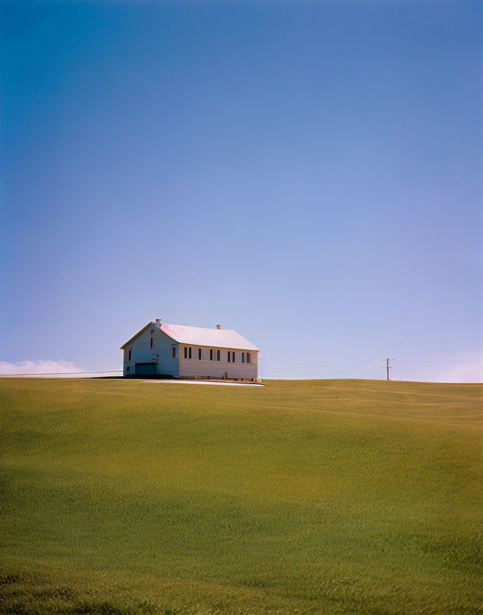 House on Green Hill under Blue Sky with Utility Pole