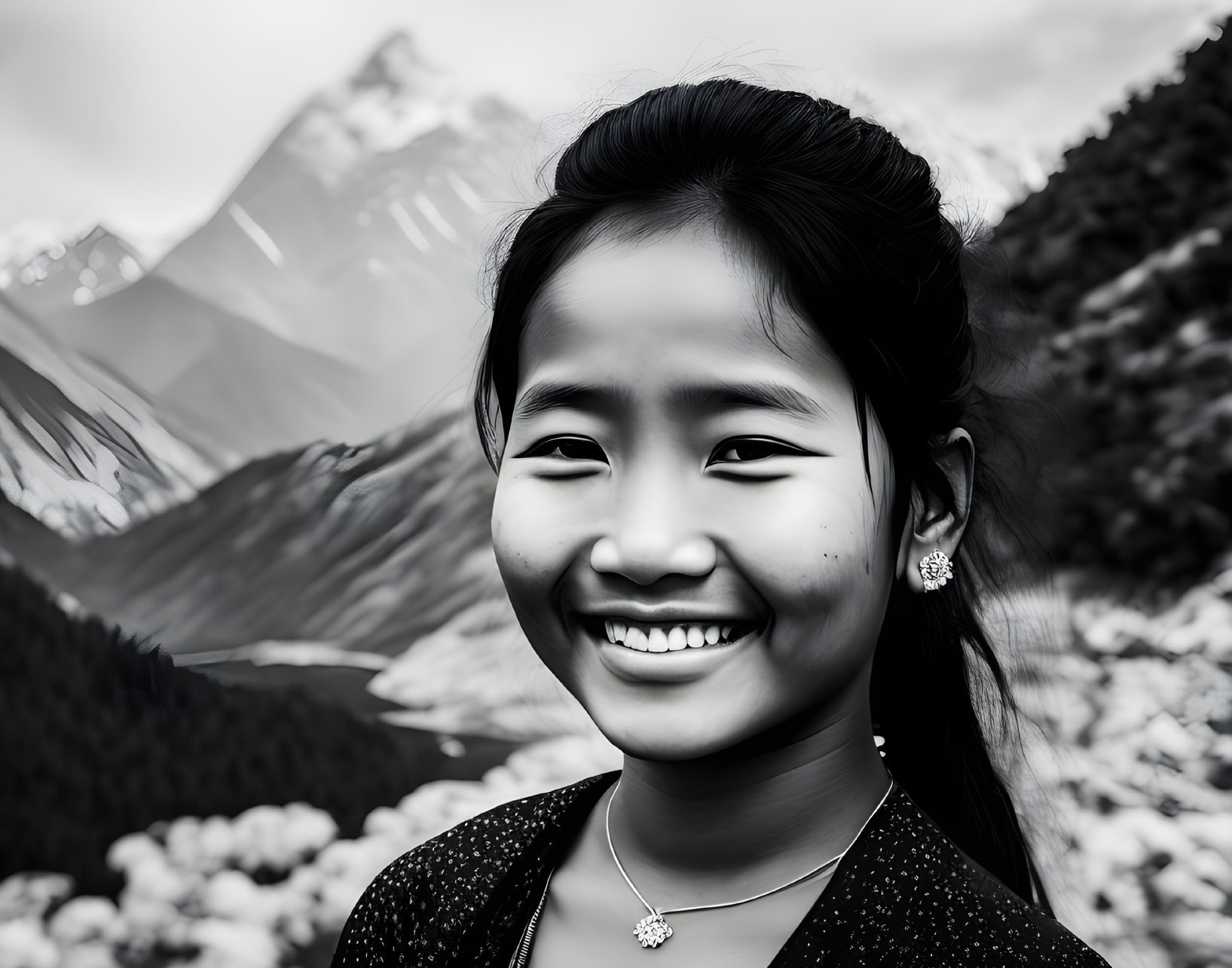 Smiling girl with earrings and necklace in black and white photo