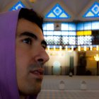 Man in Purple Head Covering with Stained Glass Windows and Chandelier