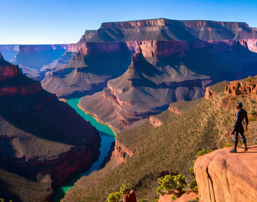 Person standing on cliff overlooking winding river in colorful Grand Canyon