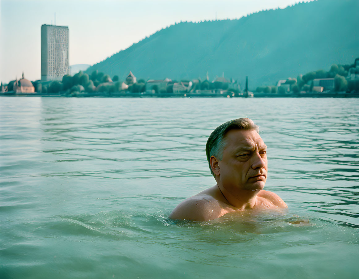 Man swimming with cityscape and hills on hazy day