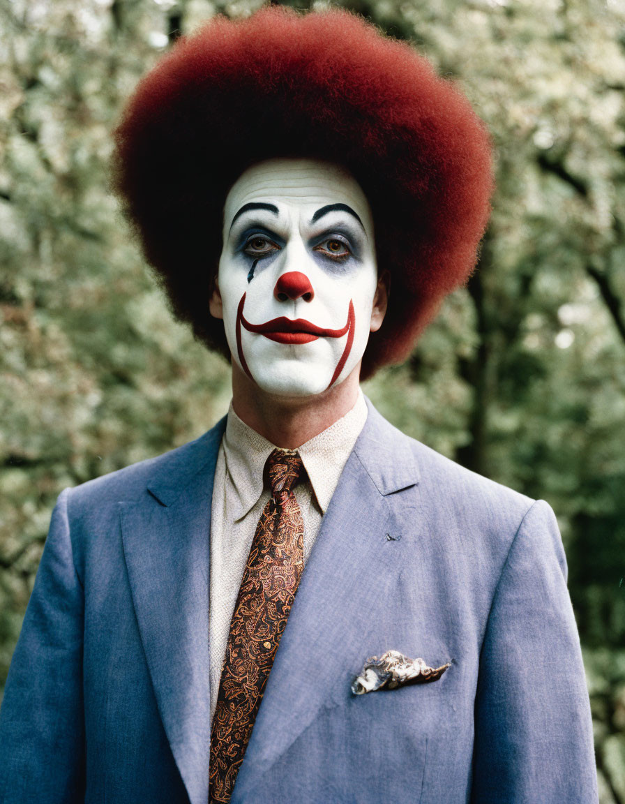 Clown makeup with red afro wig and blue suit outdoors