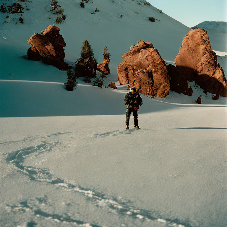 Astronaut in snowy alien landscape with rocks and shrubs