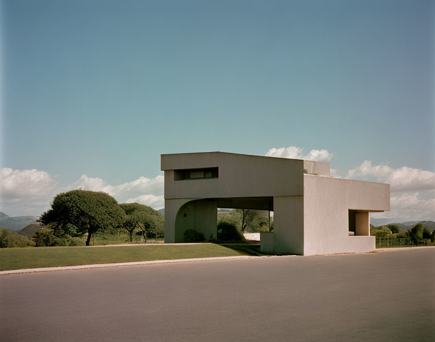 Modern architectural building with geometric shapes near road and trees.