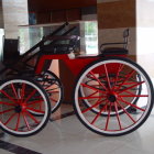 Vintage Red and Black Car with Large Spoked Wheels Displayed Indoors