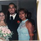 Elegantly dressed group in car: women in blue gowns, man in suit with rose bout