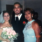 Wedding photo with smiling trio in black and white attire and roses bouquet