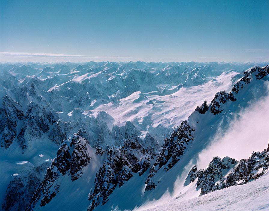 Snow-capped mountain peaks under clear blue skies: rugged beauty captured in shadows.