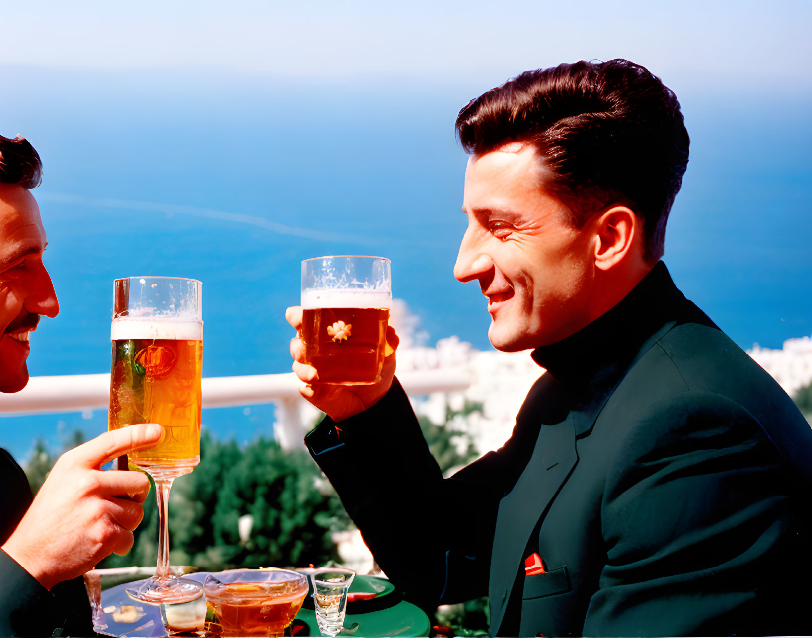 Men in suits toasting with beer glasses by the coast under blue sky