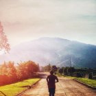 Scenic mountain path jogging at sunrise with mist and light rays