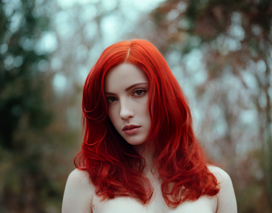 Vibrant red-haired woman with intense gaze in natural setting