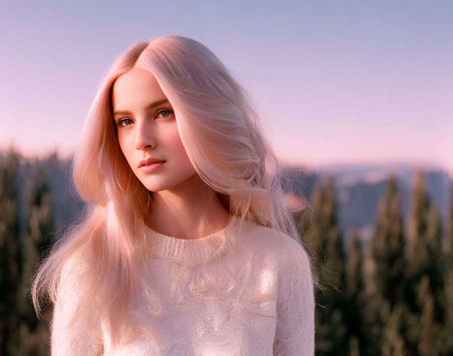 Woman with long pink hair in white sweater against sunset backdrop