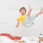 Children sleeping on bed with floating child in surreal room with gravity-defying clock and toy