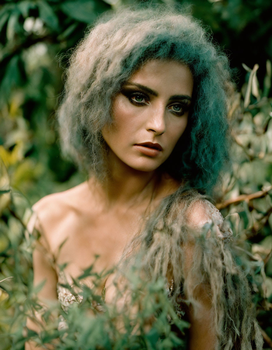 Woman with striking eyes and wild grey hair in lush greenery