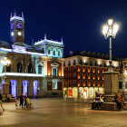 Vibrant evening square with illuminated buildings and people, exuding cozy atmosphere