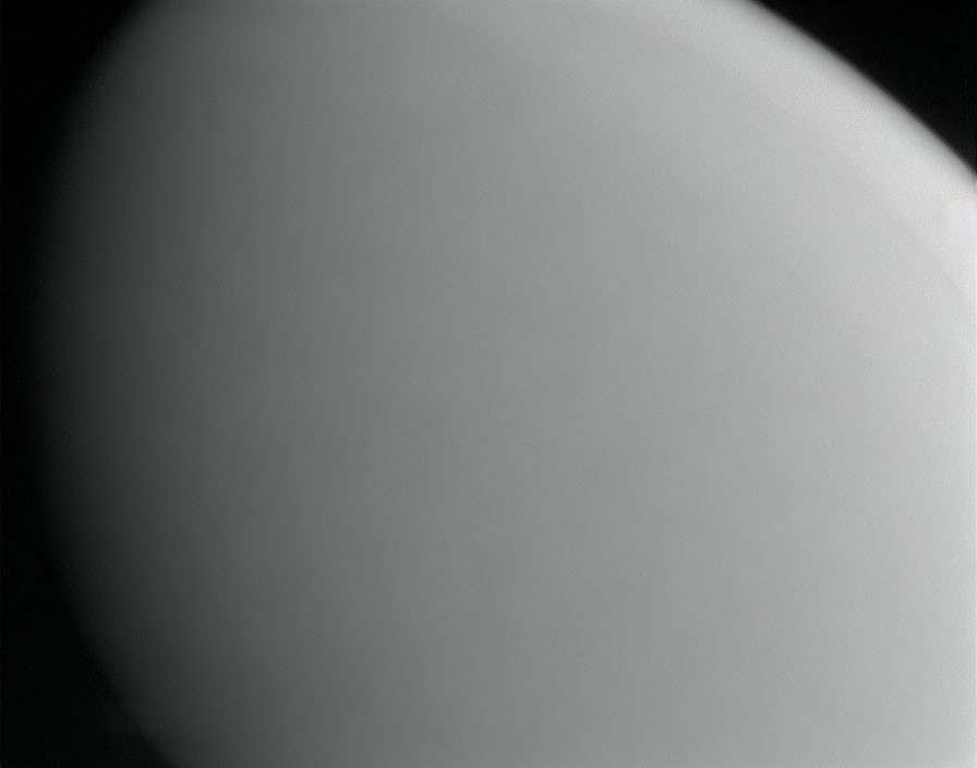 Celestial body with smooth, shadowed surface and crescent light edge