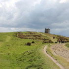 Scenic landscape: castle on hill, flower fields, cloudy sky