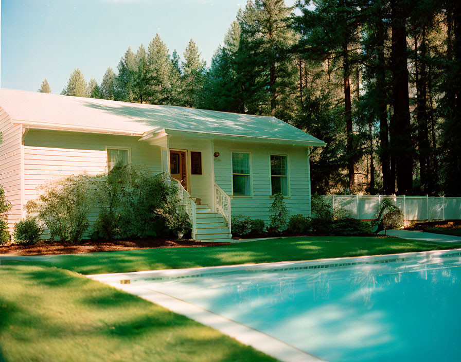 White House with Front Porch, Pine Trees, and Pool on Sunny Day