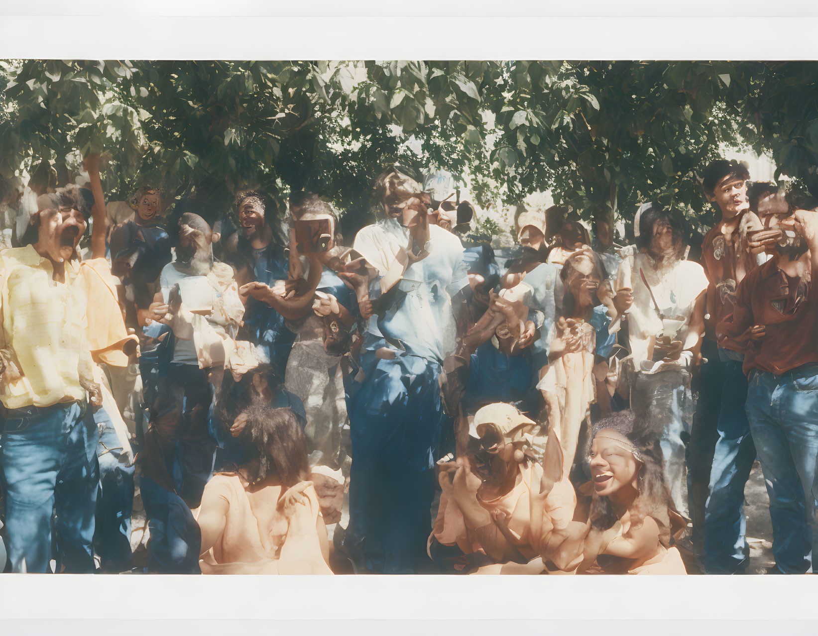 Crowd of people celebrating or protesting under a tree