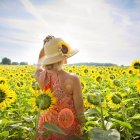 Girl with bouquet in vibrant flower field with sailboats in distance