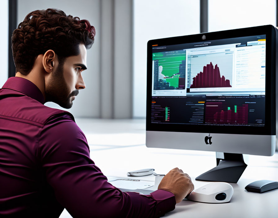 Man analyzing financial data on desktop computer with graphs and charts.