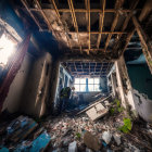 Decrepit room with damaged staircase, peeling paint, debris, and icicles