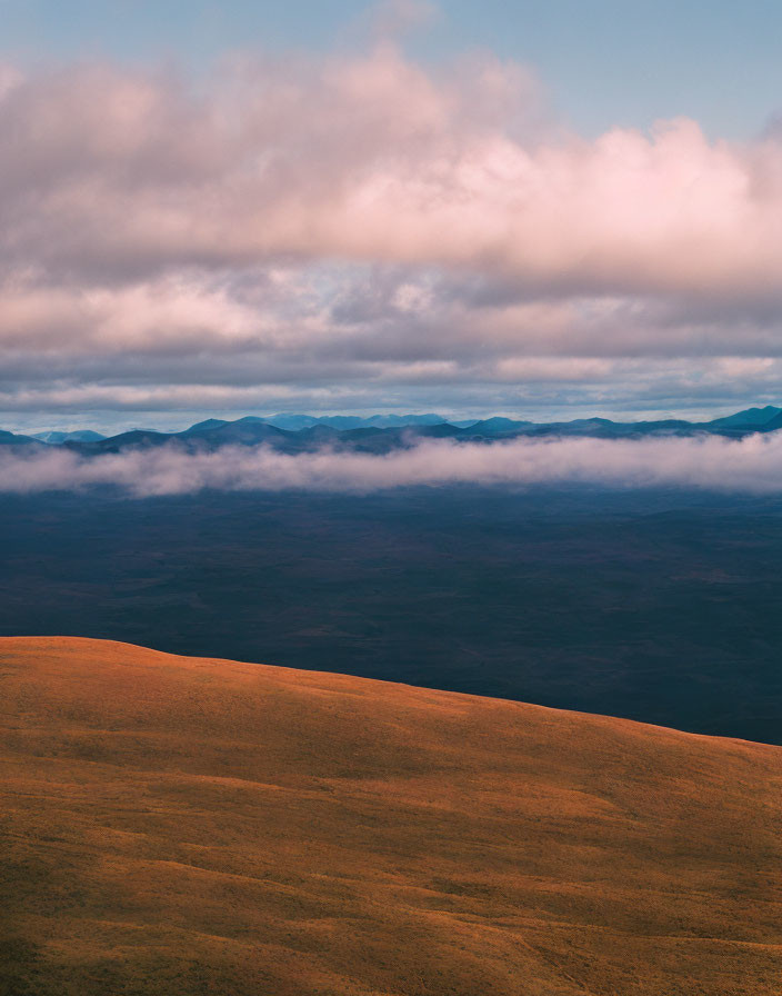 Golden Hill and Misty Mountain Landscape Under Cloudy Sky