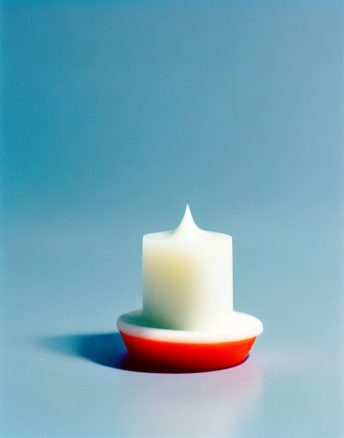 White Pointed Tip Pillar Candle on Red Dish against Blue Gradient Background