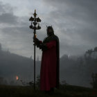 Robed figure in armor with staff in misty forest landscape