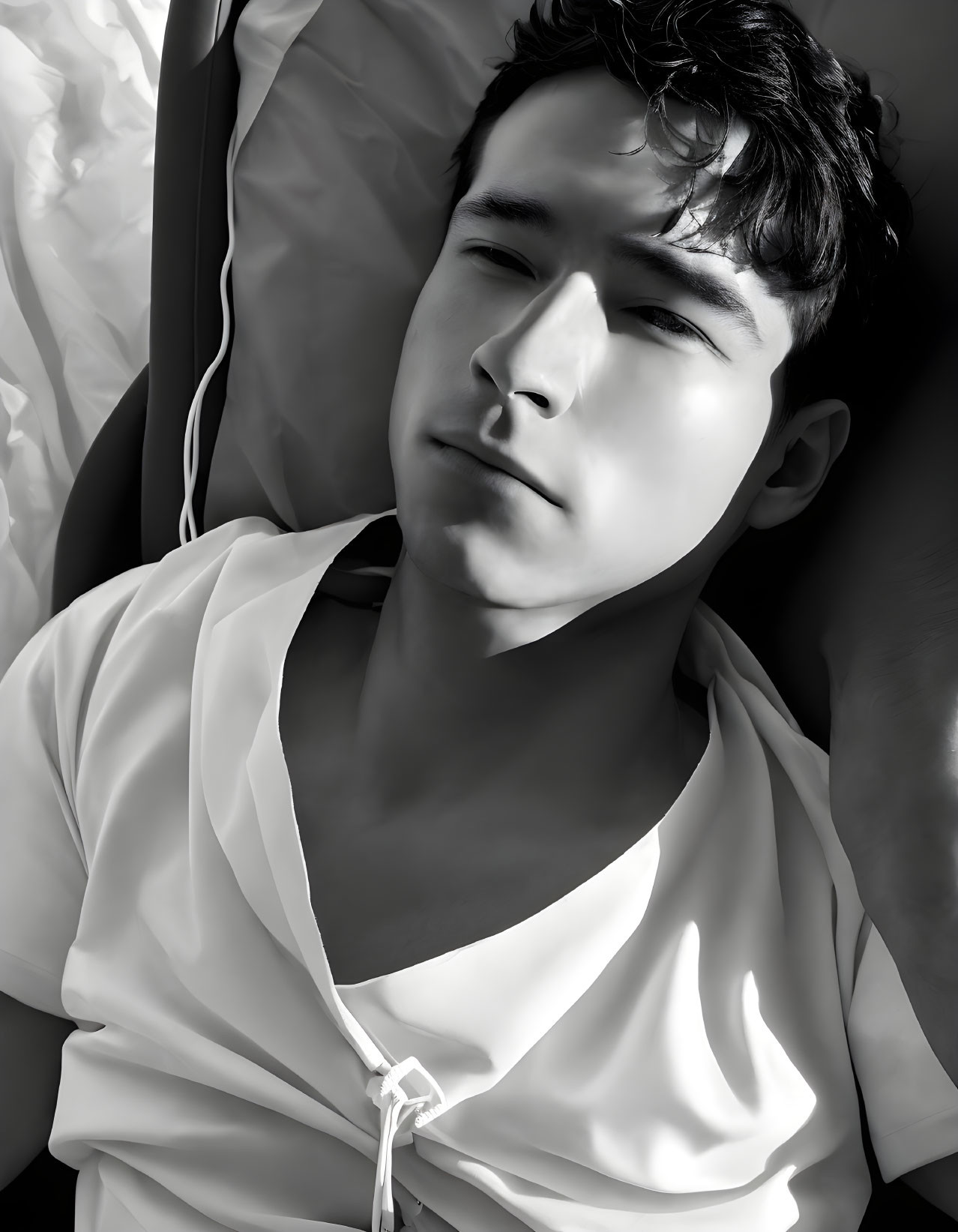 Monochrome image: young man resting with eyes closed under sunlight
