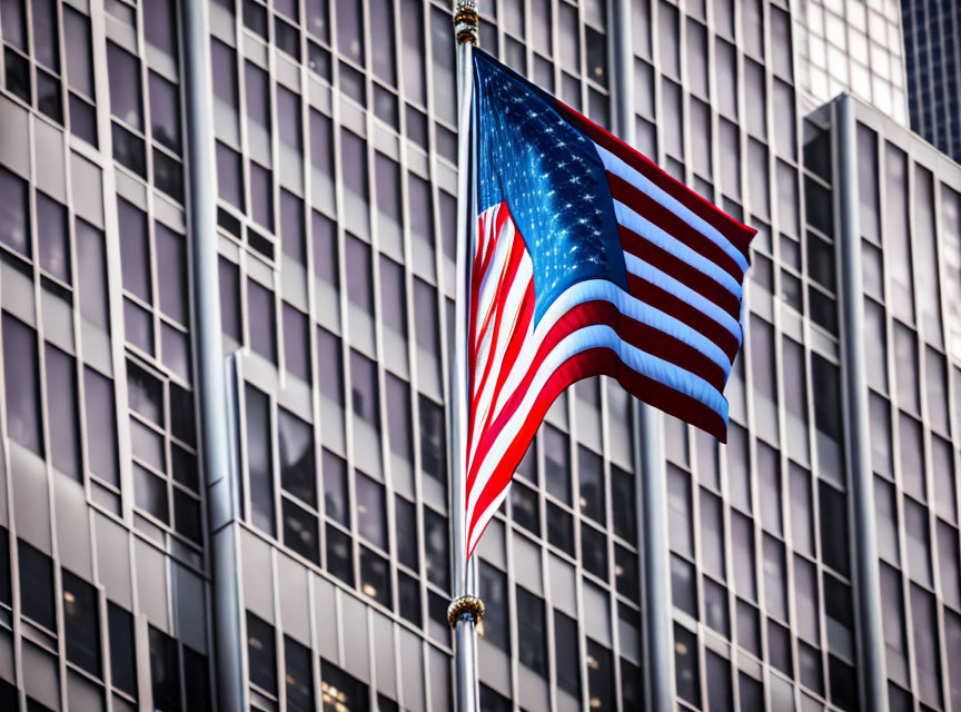 American flag displayed in front of modern glass skyscraper