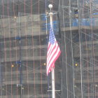 American flag displayed in front of modern glass skyscraper