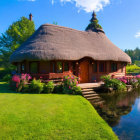 Rustic wooden cabin by serene pond with lush greenery and blue sky