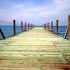 Scenic wooden jetty over turquoise sea and cloudy sky