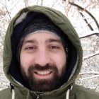 Man with Blue Eyes in Green Hooded Jacket with Snowflakes