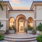 Symmetrical White Mansion with Columns and Topiary Bushes at Dusk