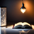 Sculpted table lamp beside open book, reading glasses on desk