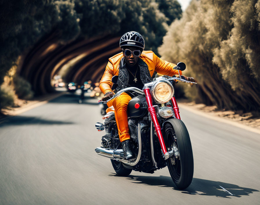 Motorcyclist in orange jacket and sunglasses rides on road with tunnel and trees